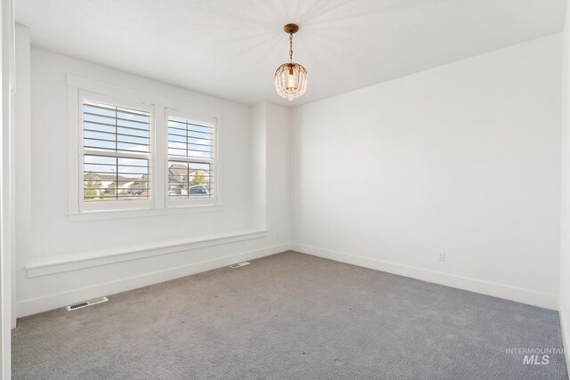 spare room featuring a chandelier and carpet floors