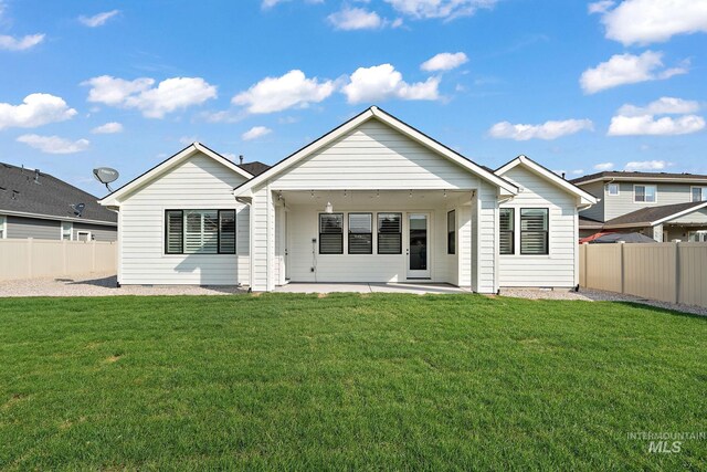 rear view of house featuring a lawn and a patio