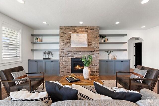 living room with a brick fireplace, light hardwood / wood-style flooring, and built in features