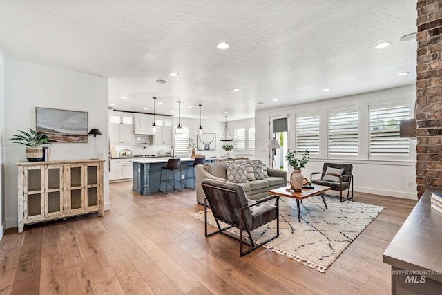 living room featuring light hardwood / wood-style flooring, a textured ceiling, and sink