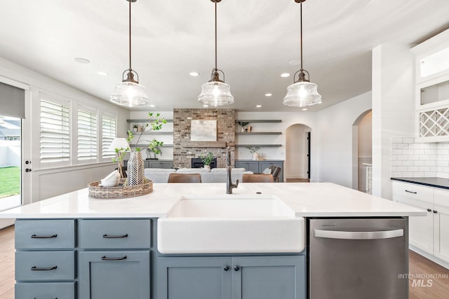 kitchen featuring a brick fireplace, backsplash, dishwasher, and hanging light fixtures