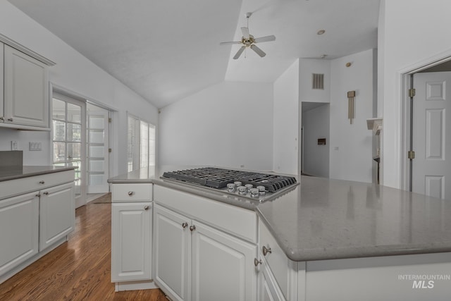 kitchen featuring lofted ceiling, wood finished floors, stainless steel gas cooktop, visible vents, and ceiling fan