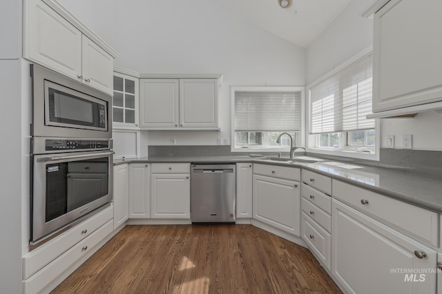kitchen with lofted ceiling, stainless steel appliances, white cabinets, and a sink