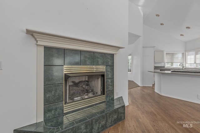 details with baseboards, a tiled fireplace, and wood finished floors