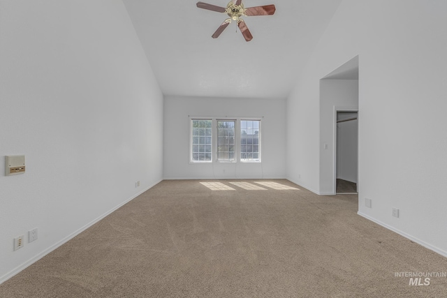 carpeted spare room featuring baseboards, ceiling fan, and vaulted ceiling