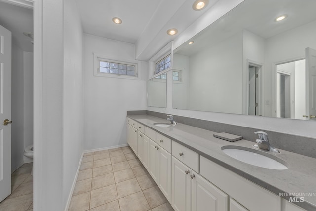 bathroom with toilet, recessed lighting, double vanity, and a sink
