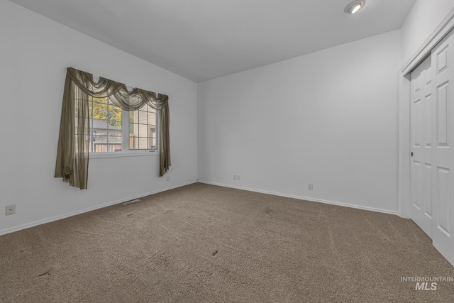 unfurnished room with baseboards, visible vents, and carpet