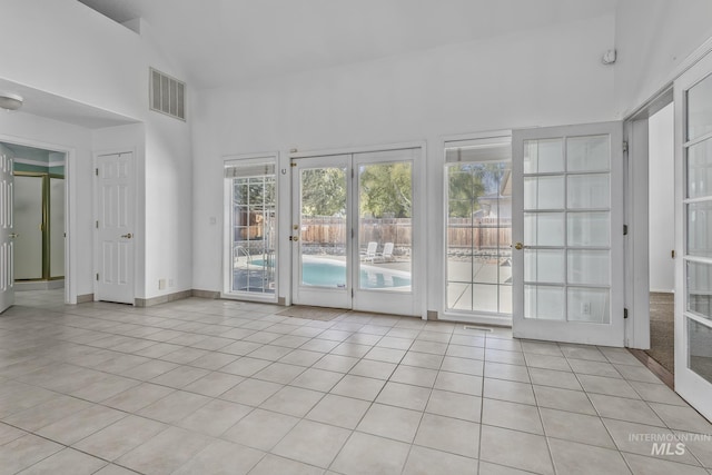 interior space with light tile patterned floors, visible vents, french doors, and high vaulted ceiling