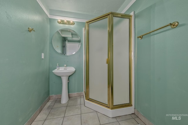 bathroom with a stall shower, baseboards, tile patterned floors, and a sink