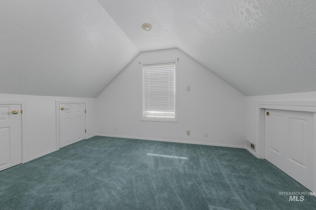 additional living space with lofted ceiling, a textured ceiling, baseboards, carpet flooring, and visible vents