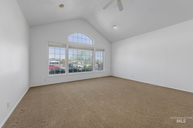 carpeted empty room featuring baseboards, ceiling fan, and vaulted ceiling