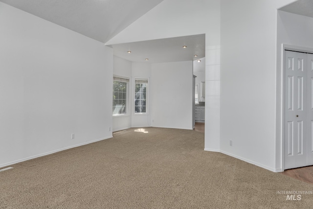 empty room featuring carpet, baseboards, and high vaulted ceiling