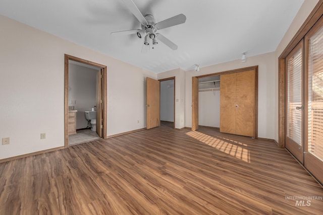 unfurnished bedroom with a closet, wood finished floors, baseboards, ceiling fan, and ensuite bath