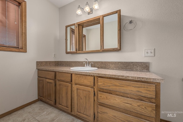 bathroom with vanity, baseboards, and tile patterned flooring