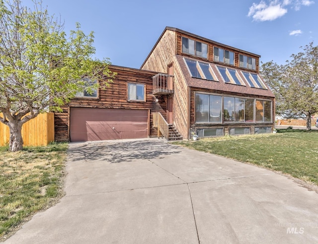 view of front facade featuring fence, driveway, a front lawn, and a garage
