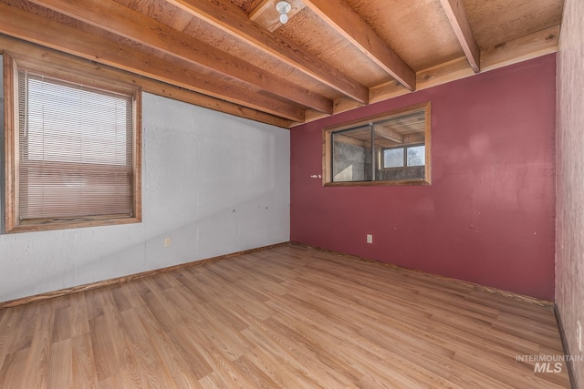 empty room featuring beamed ceiling, baseboards, and light wood-style flooring