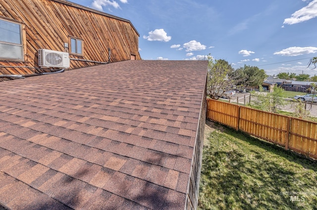 details featuring a shingled roof, fence, and ac unit