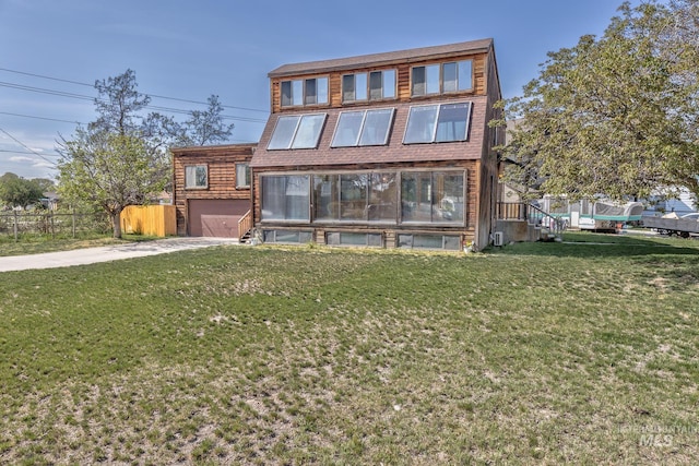 contemporary home with a garage, a front lawn, fence, and concrete driveway