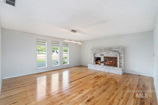 7301 W Diamond St, Boise, ID 83709 - unfurnished living room with wood finished floors, baseboards, and a brick fireplace