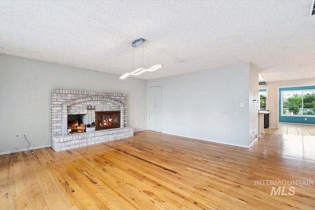 7301 W Diamond St, Boise, ID 83709 - unfurnished living room featuring wood-type flooring, baseboards, and a brick fireplace