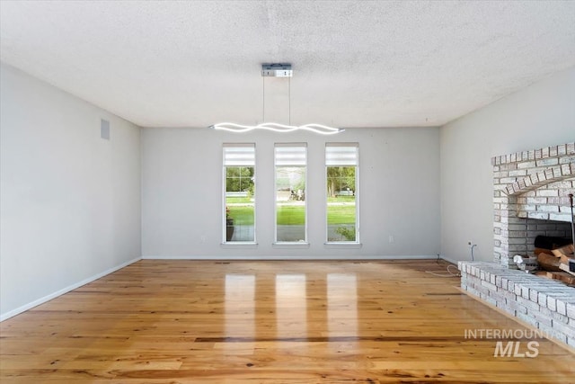 7301 W Diamond St, Boise, ID 83709 - unfurnished living room with light wood-style flooring, a fireplace, baseboards, and a textured ceiling