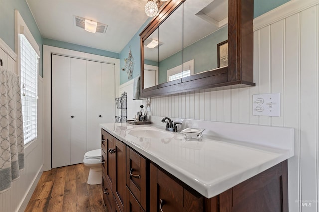 bathroom with hardwood / wood-style flooring, a healthy amount of sunlight, vanity, and toilet