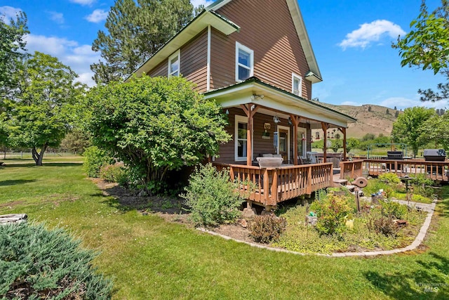 rear view of property with a lawn and a deck with mountain view