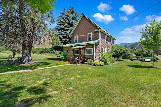 rear view of property featuring a mountain view and a lawn