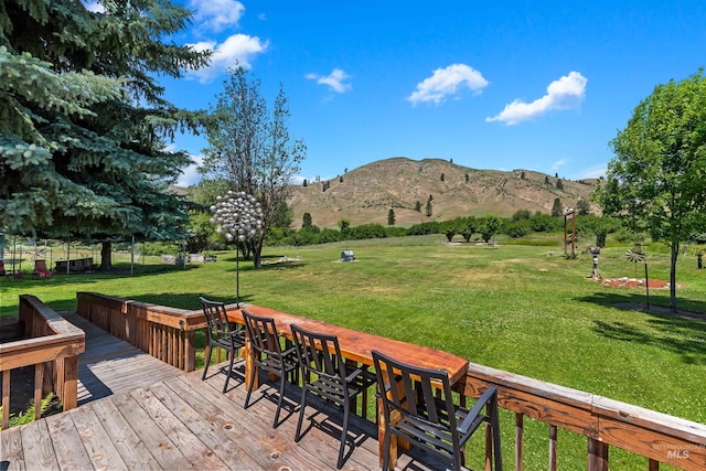 deck featuring a mountain view and a lawn