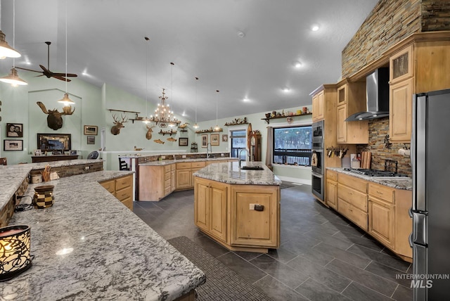 kitchen featuring appliances with stainless steel finishes, light stone counters, wall chimney range hood, pendant lighting, and a large island