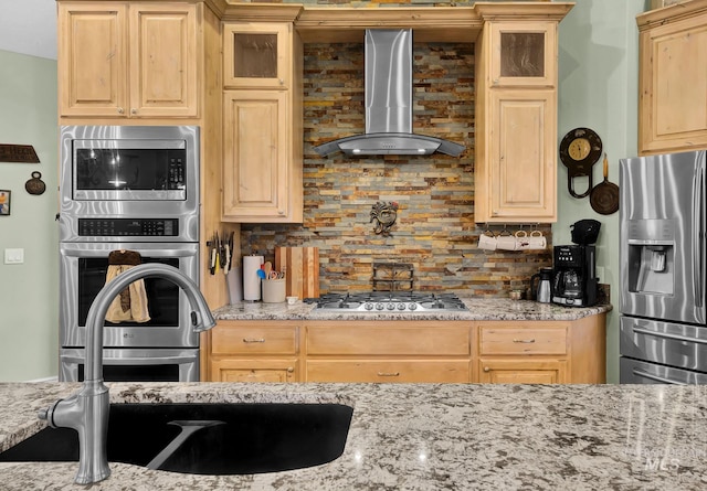 kitchen with appliances with stainless steel finishes, backsplash, light stone counters, and wall chimney exhaust hood