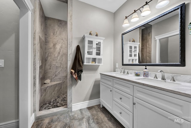 bathroom featuring wood-type flooring, vanity, and a tile shower