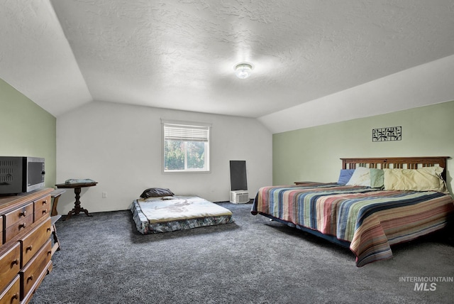 bedroom featuring dark colored carpet, lofted ceiling, and a textured ceiling