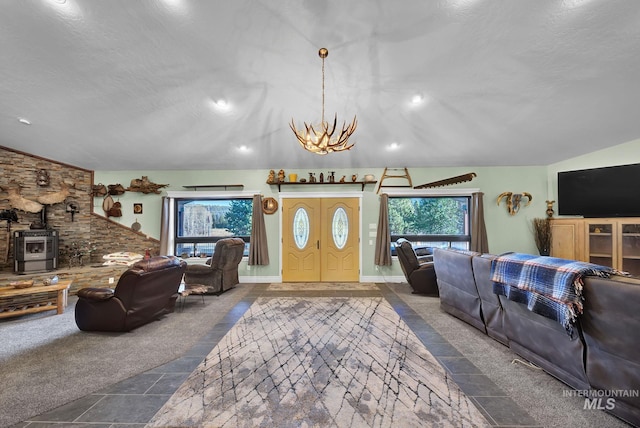 carpeted living room with a wood stove, plenty of natural light, a chandelier, and lofted ceiling