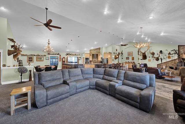 carpeted living room with ceiling fan with notable chandelier and high vaulted ceiling