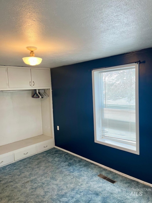 carpeted empty room featuring baseboards, visible vents, and a textured ceiling