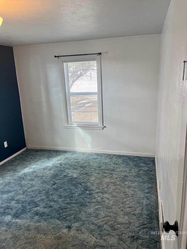 carpeted empty room featuring baseboards