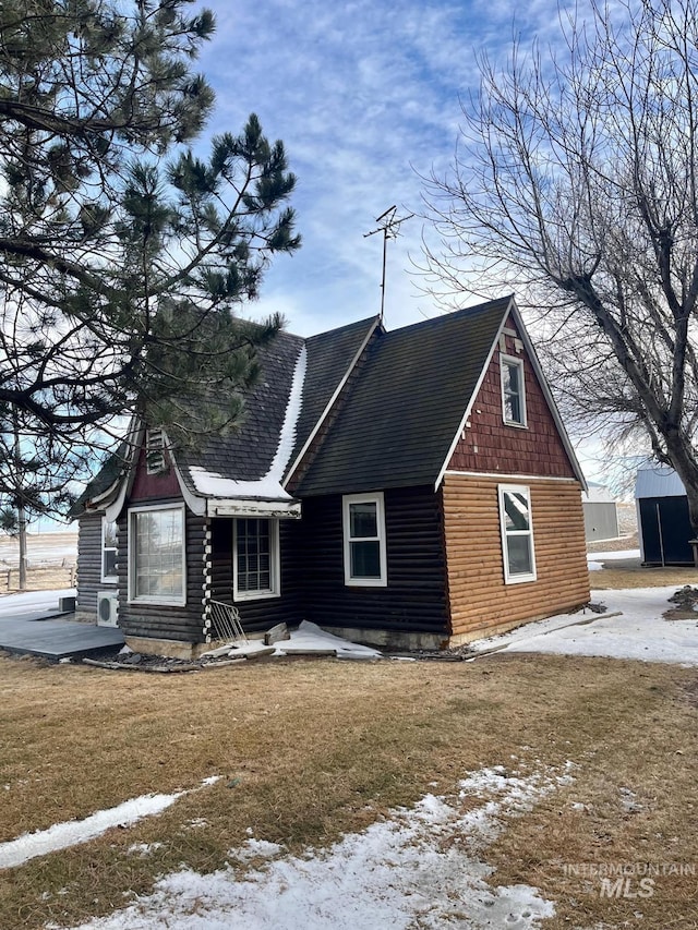 view of snowy exterior featuring a yard and a shingled roof