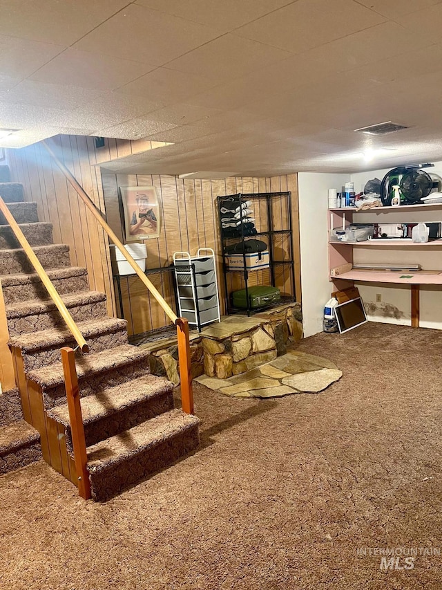 finished below grade area with stairs, wood walls, and carpet floors