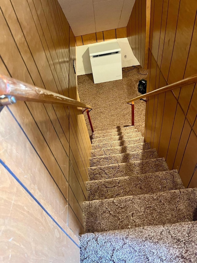 stairway featuring wood walls