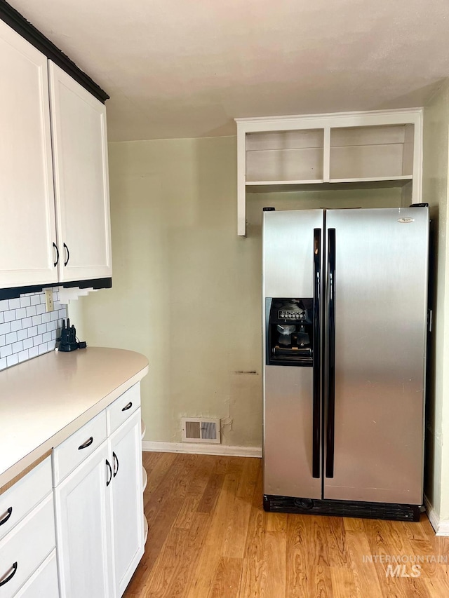 kitchen with visible vents, light countertops, baseboards, light wood finished floors, and stainless steel refrigerator with ice dispenser