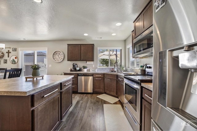 kitchen with dark hardwood / wood-style flooring, a center island, stainless steel appliances, and a textured ceiling