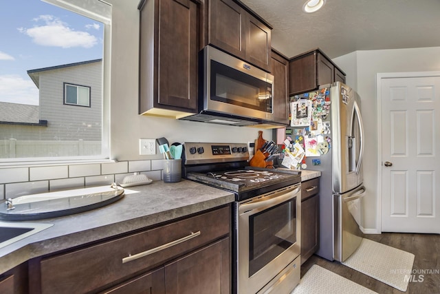 kitchen featuring appliances with stainless steel finishes, a textured ceiling, light hardwood / wood-style floors, and dark brown cabinets