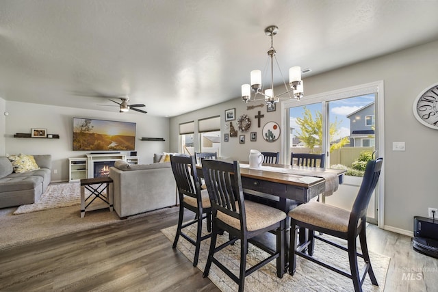 dining room with hardwood / wood-style floors, a healthy amount of sunlight, and ceiling fan with notable chandelier