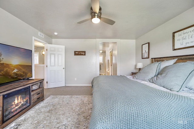 carpeted bedroom with ensuite bathroom and ceiling fan