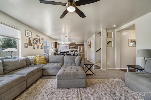 carpeted living room featuring ceiling fan with notable chandelier