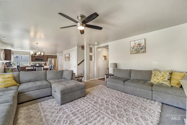 living room featuring light carpet and ceiling fan with notable chandelier