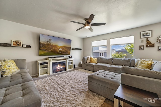 living room with a textured ceiling, carpet floors, and ceiling fan