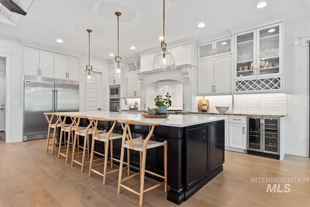 1552 W Windbreaker Ln, Eagle, ID 83616 - kitchen with wine cooler, built in appliances, light wood-style floors, tasteful backsplash, and recessed lighting