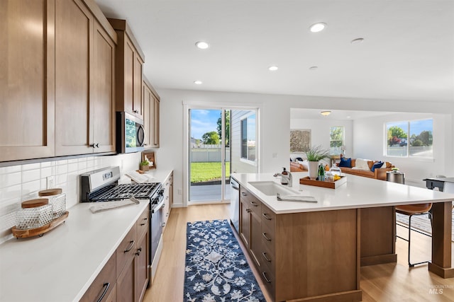 kitchen featuring appliances with stainless steel finishes, a sink, healthy amount of natural light, light wood-style flooring, and recessed lighting